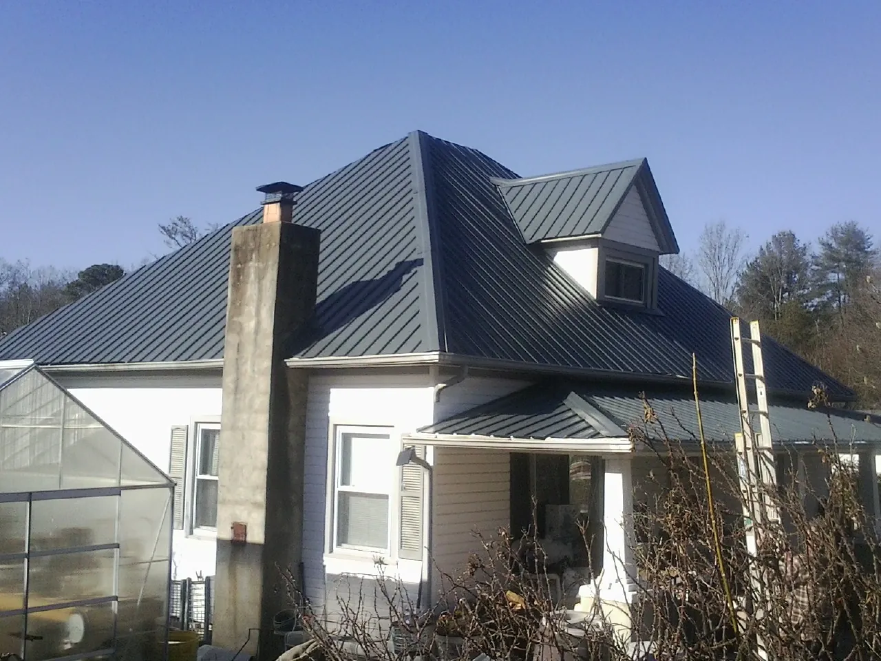 Dark blue standing seam metal roof on a white farmhouse with dormer — Slate & Tile Roof Repair by Roofing Brothers in Hyrum