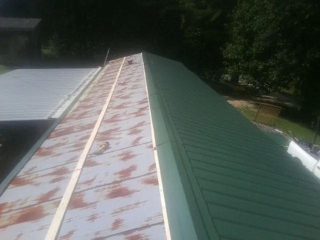 Old rusted panels beside newly installed green metal roofing — Wind Damage Roof Repair by Roofing Brothers in Hyrum
