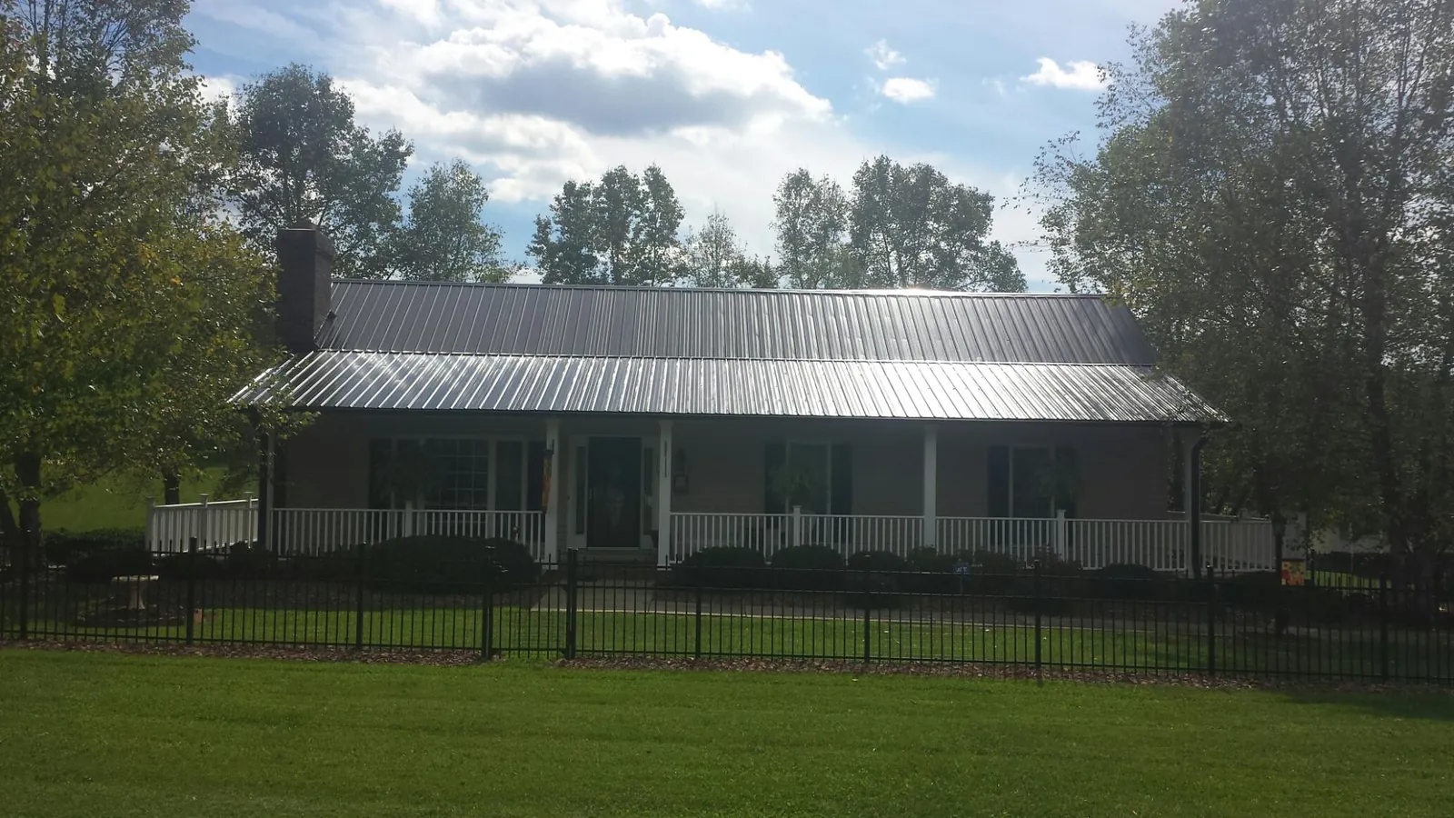 Gray metal roof on a brick ranch with a full width front porch — Gutter Guard Installation work by our crew in Hyrum