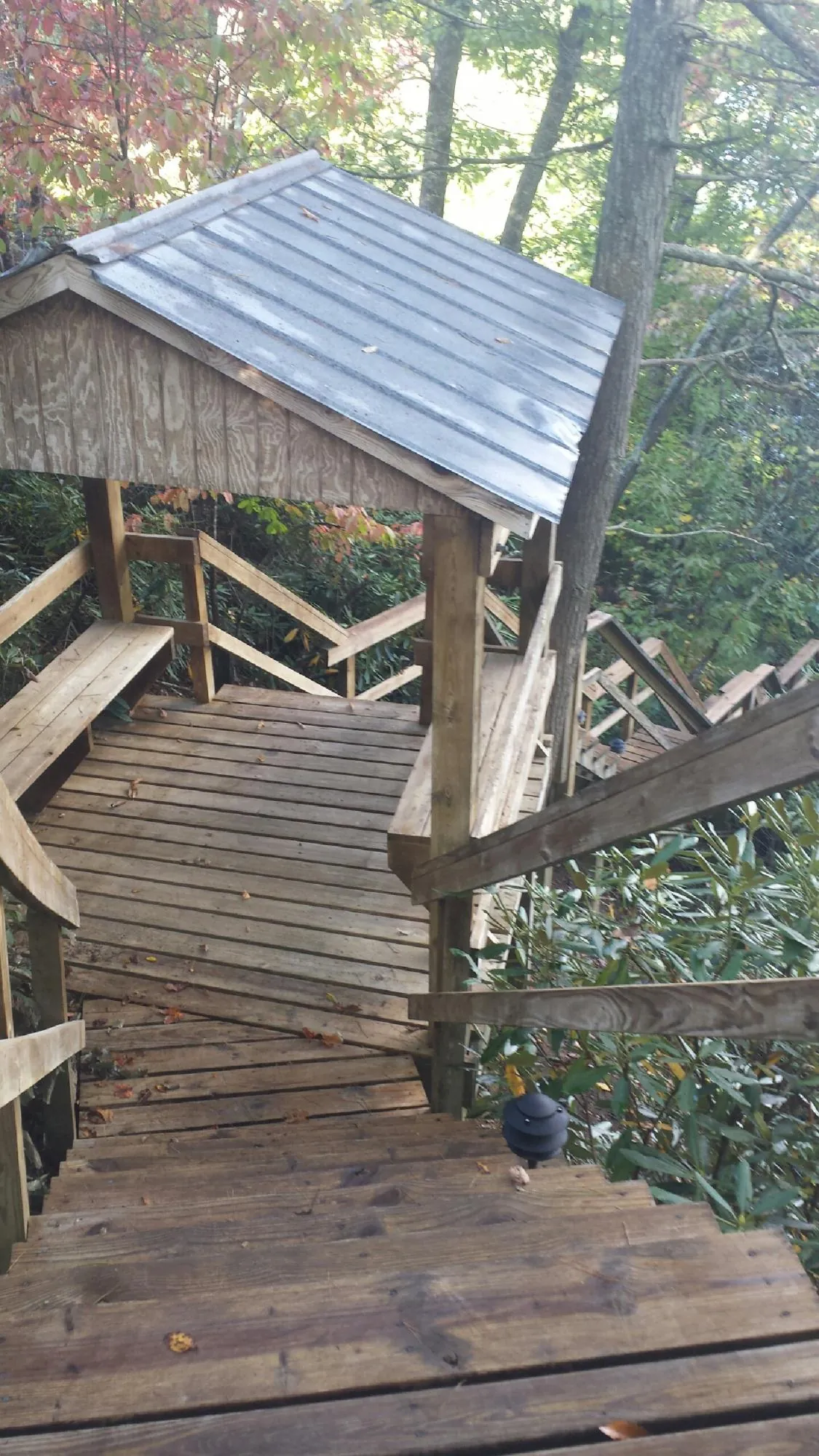 Metal roofed shelter over wooden steps on a wooded walkway — Skylight Repair & Installation work by our crew in Hyrum