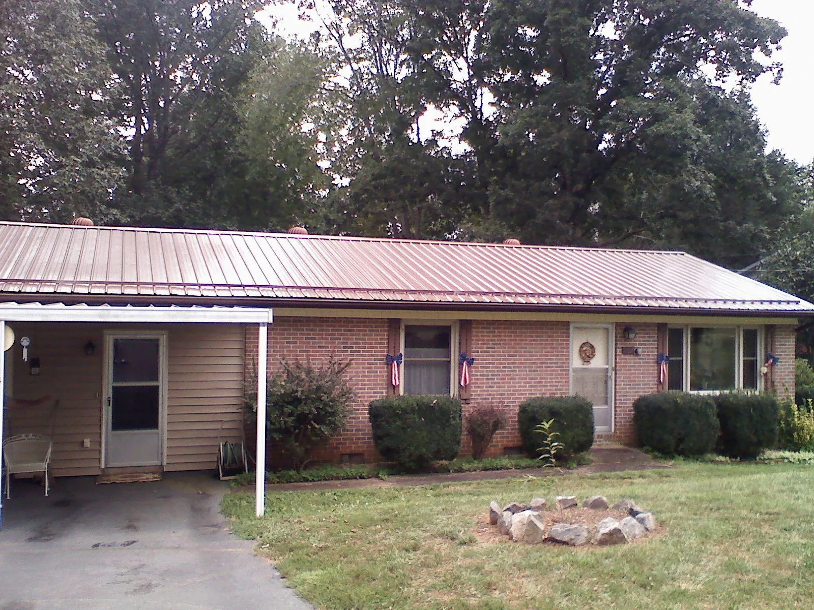 Bronze metal roof and carport on a brick ranch home — Roof Repair work by our crew in Hyrum